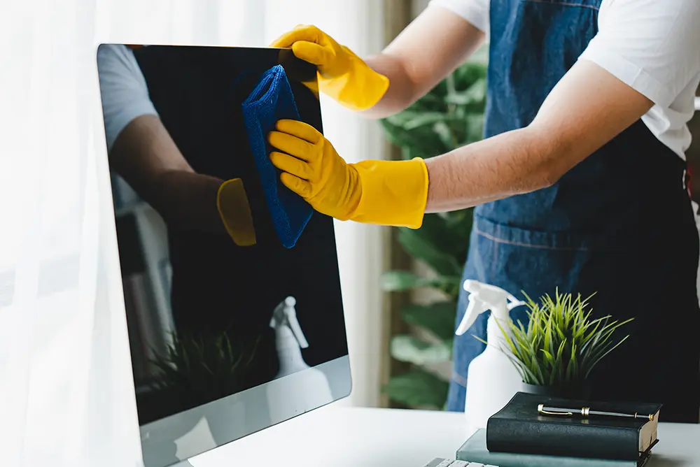 Die Reinigungskräfte verwenden Tücher und sprühen Desinfektionsmittel. Wischen Sie den Schreibtisch und den Boden im Büroraum.